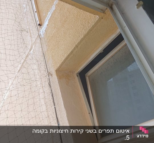 חלון פתוח עם רשת בטיחות על קיר חיצוני